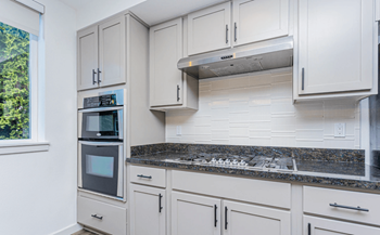 A kitchen with white cabinets and a granite countertop.